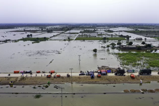 photo of aid being dropped off on a road elevated above flooding in Pakistan
