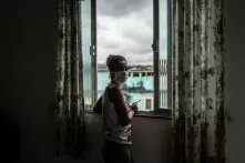 A woman stands with a phone in a window in Brazil