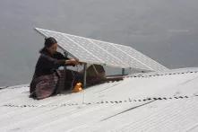 A woman installing solar panels on a roof in Bhutan