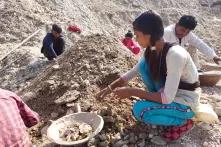 young girl sifts through mica debris