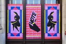 Three banners showing dancing people and someone voting