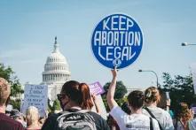 Woman holds sign that says "keep abortion legal" at protest with US Capitol building in background