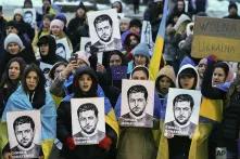 Protestors with Ukrainian flags and photos of Ukrainian president Volodymyr Zelenskyy