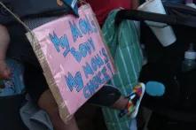 protest sign in front of US supreme court draped over a baby that says "my mom's body my mom's choice"