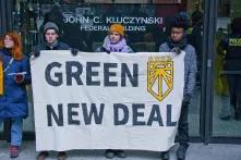 protesters hold up banner that says "green new deal"
