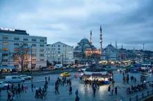 plaza with people on it in front of modern apartment buildings and a very old religious structure