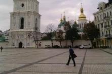man walking across large city square with religious buildings in the background