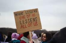 protester holding sign that says "what lessens one of us lessens all of us"