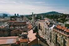 european city on a sunny day with a mountain and radio tower in the background