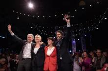 4 people standing in a full auditorium with their arms raised