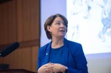 women in blue suit speaking at podium
