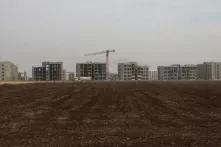 buildings behind a field tilled for farming