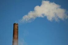 a smokestack emitting smoke against a blue sky