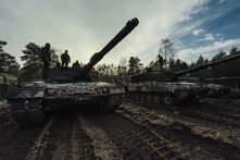 men stand on a tank parked in a muddy forest