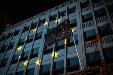 European Union flag in front of a building with the EU stars projected onto it at night