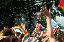 hands, bubbles, and pride flags waving in the air at a parade