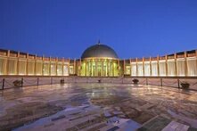 a plaza in front of a curved building with a dome in the middle