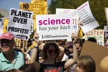woman holding a protest sign that says "science has your back"