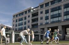 statue of children and grandparents playing in front of a large building