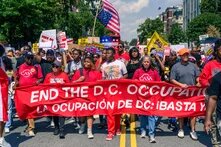 Protestors holding a red banner that says, "End the D.C. Occupation"