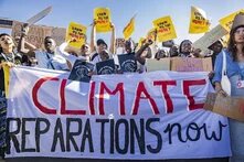 protestors demand climate reparations with a large banner