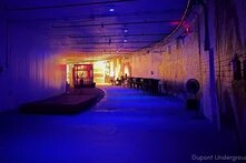 a long, unlit event space barely curving left with light at the far end