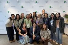 a group of people stand in three rows in front of a wall with the Green Climate Fund logo