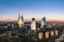 three tall buildings at sunset over a large city