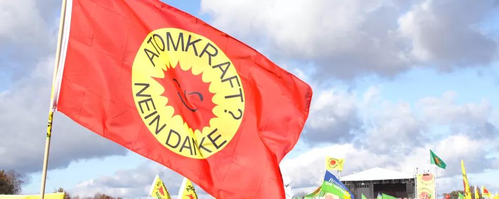 flag saying "atomic energy? no thanks" in front of a big rally
