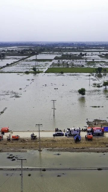 photo of aid being dropped off on a road elevated above flooding in Pakistan