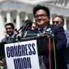 man standing at a podium with microphones and a sign that says "congress union" in front of the Capitol Building