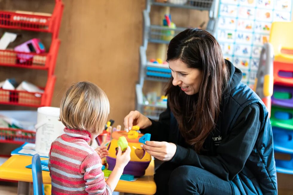 Woman plays with child in school