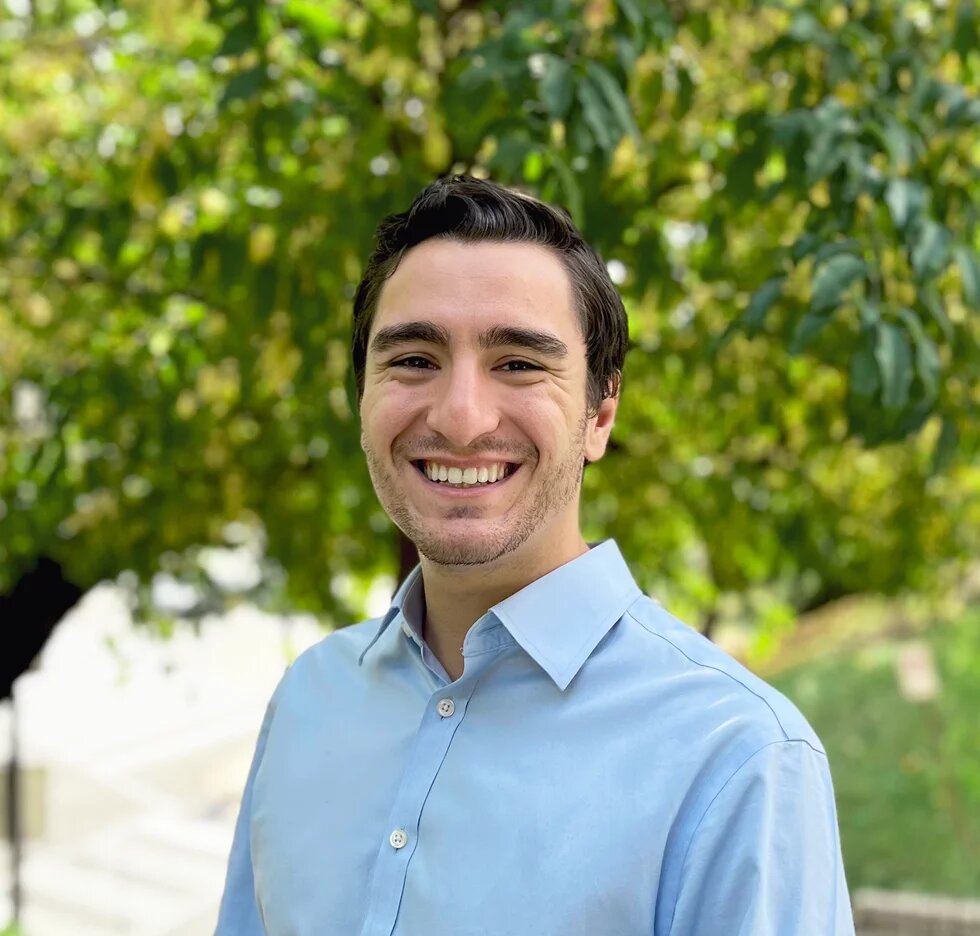 headshot of ben davis in front of green, leafy background