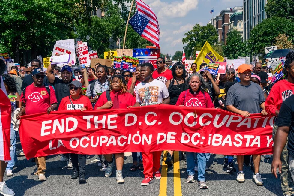 Protestors holding a red banner that says, "End the D.C. Occupation"