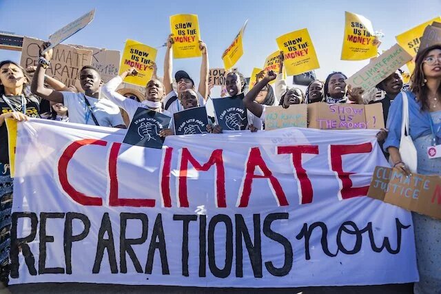 protestors demand climate reparations with a large banner