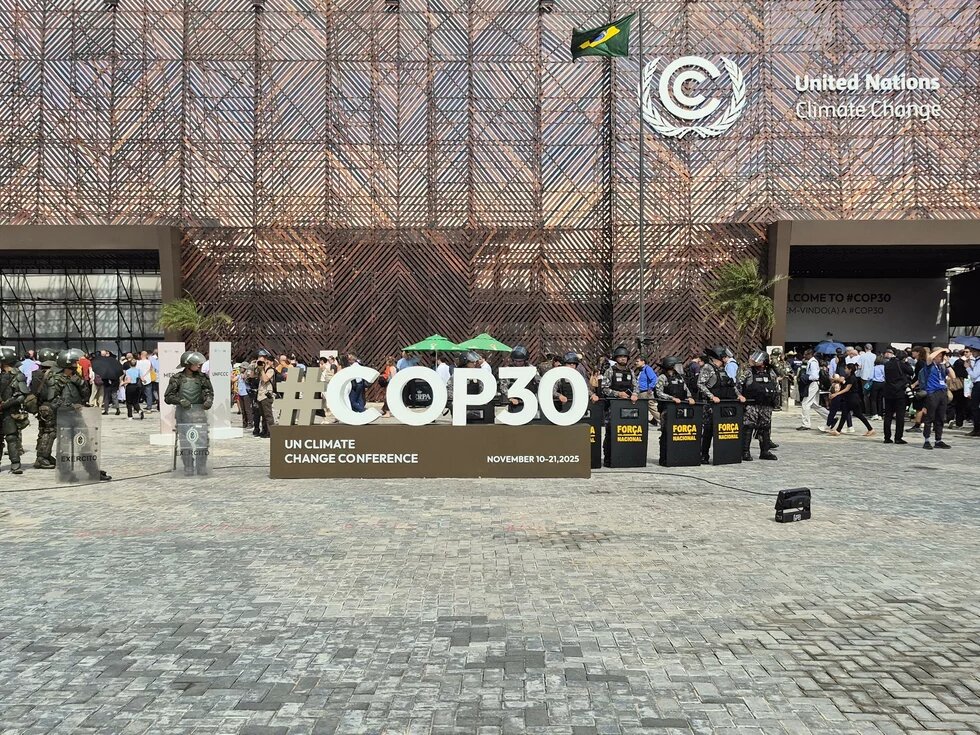 Riot police standing next to the COP30 sign at the conference center in Belem